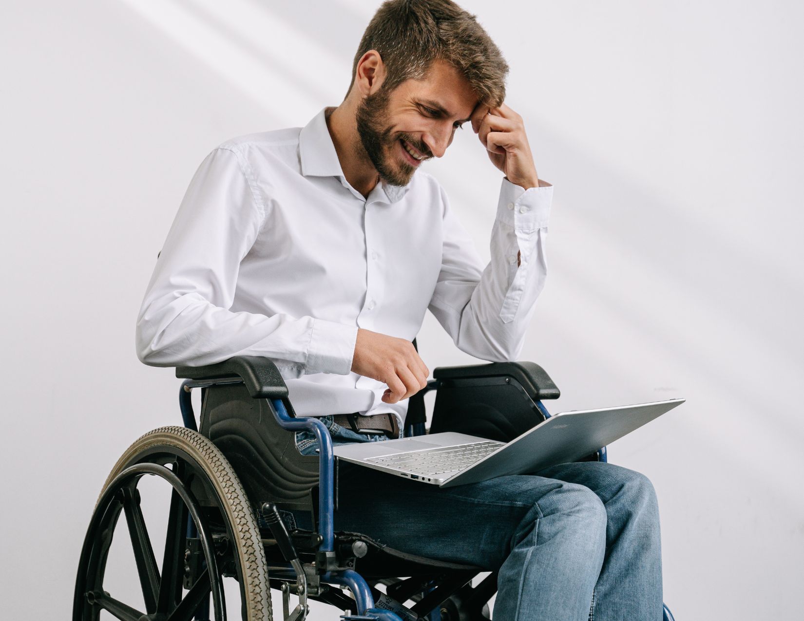 Middle aged man in wheelchair with laptop smiling